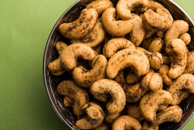 Um punhado de castanhas de caju torradas com especiarias ou masala kaju servido em uma tigela, com foco seletivo