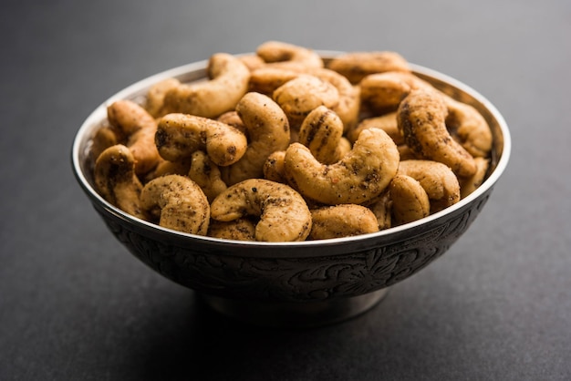 Um punhado de castanhas de caju torradas com especiarias ou masala kaju servido em uma tigela, com foco seletivo