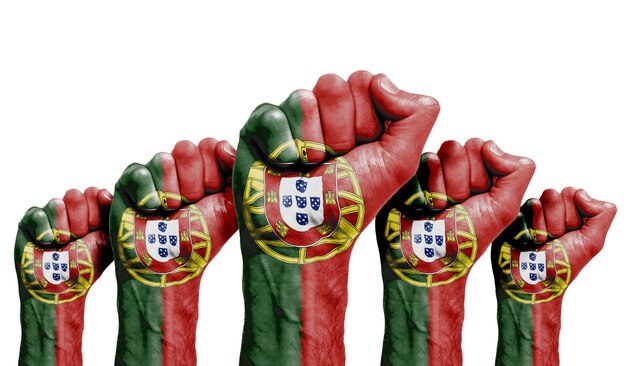 Foto um punho erguido de manifestantes pintados com a bandeira de portugal