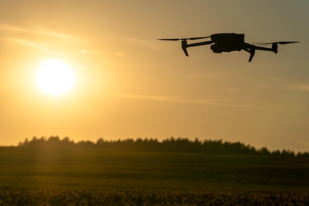 Um quadcopter moderno sobrevoa um campo de girassóis contra o pôr do sol O uso de tecnologias modernas no complexo agroindustrial O drone ajuda o agricultor no agronegócio