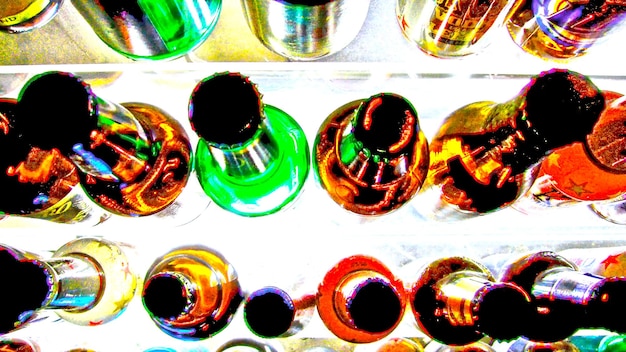 Foto um quadro cheio de garrafas coloridas na mesa.