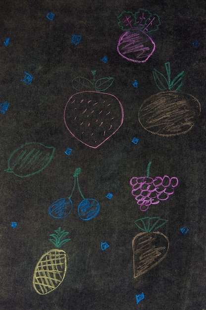 Um quadro-negro com desenhos a giz de frutas e vegetais.