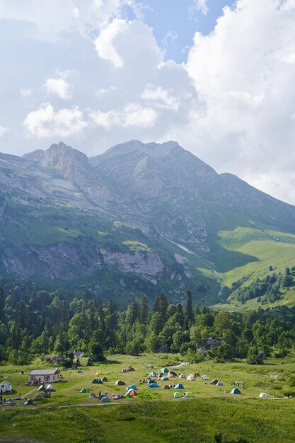 Foto um quadro vertical com uma tenda acampando em um prado montanhoso