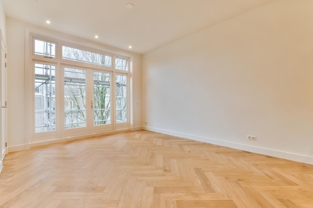 Um quarto espaçoso com piso em parquet em tons de branco e grandes janelas de bloco em uma casa aconchegante