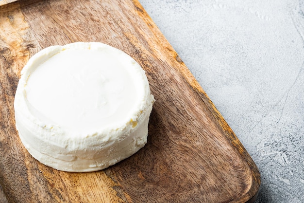 Um queijo ricota fresco na bandeja de madeira em fundo cinza com copyspace e espaço para texto