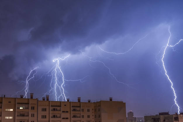 Um raio sobre a cidade no céu noturno atinge o telhado da casa.