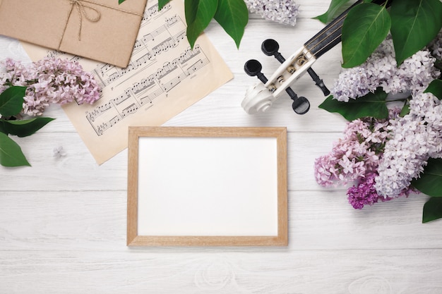 Foto um ramalhete dos lilacs com violino, placa de giz e folha de música em uma tabela de madeira branca. top wiev com espaço para o seu texto