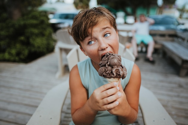 Foto um rapaz a comer um cone de gelado.