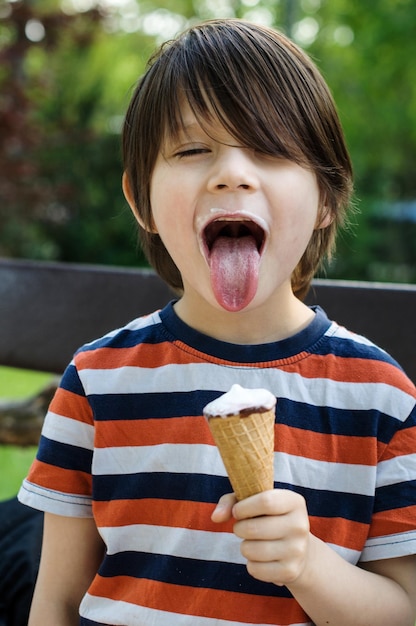 Um rapaz a puxar a língua enquanto come gelado no parque.