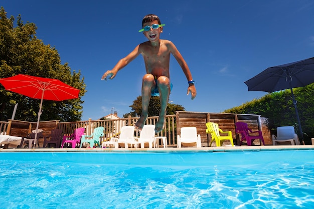 Um rapaz a saltar na piscina.