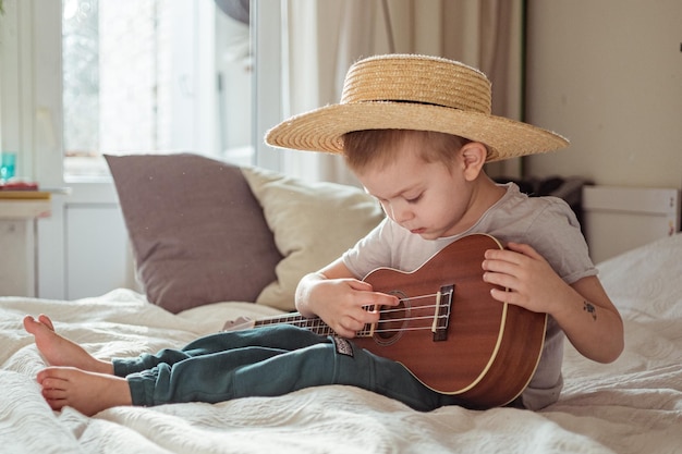 Um rapaz bonito a tocar ukulele na cama.