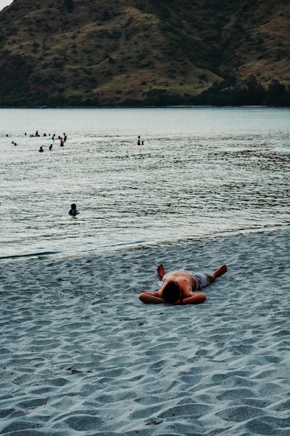 Foto um rapaz deitado na praia.