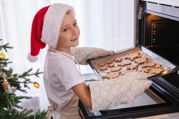 Um rapaz sorridente a colocar biscoitos no forno.