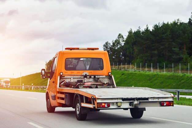 Foto um rebocador transporta um carro avariado na estrada pública a avaria do carro durante a viagem assistência rodoviária em ação