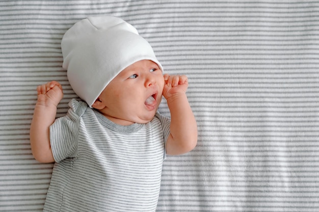 Um recém-nascido com fome Um bebê deitado em uma fralda listrada com a língua de fora pedindo leite Cuidados com o bebê