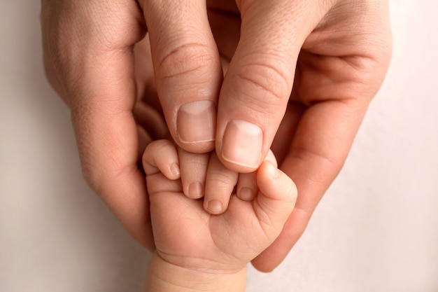 Um recém-nascido segura o dedo da mãe e do pai. fechem as mãos dos pais e do bebê. uma criança confia nela e a abraça com força. foto de alta qualidade