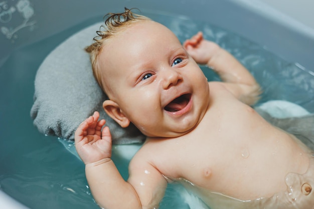 Um recém-nascido toma banho, os pais banham a criança, o recém-natado é banhado, o recê está sorrindo, os cuidados com o bebé.