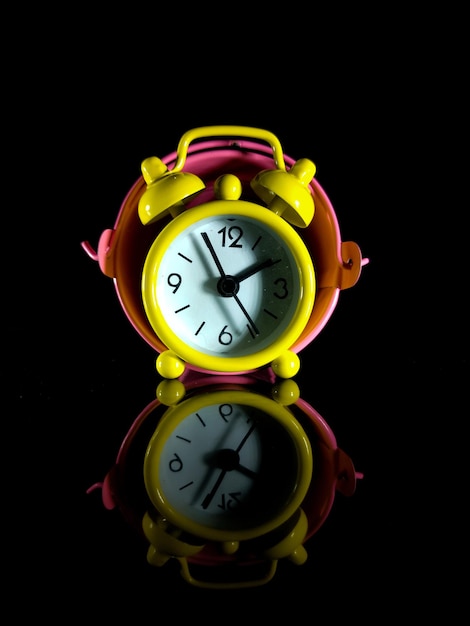Um relógio amarelo dentro do balde com reflexo em um fundo preto