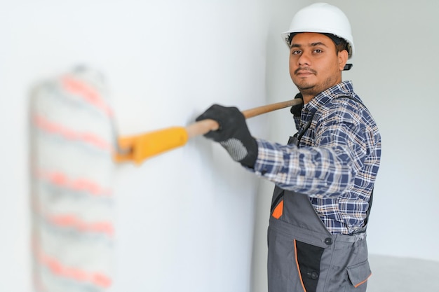 Um reparador de apartamentos indiano pinta uma parede branca com um rolo