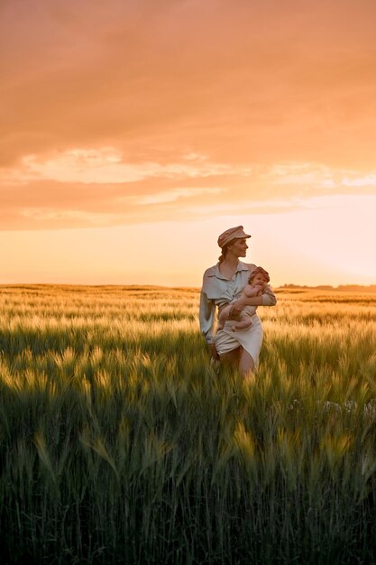 Um retrato da jovem mãe com um bebê nos braços ao pôr do sol no campo conceito de família feliz