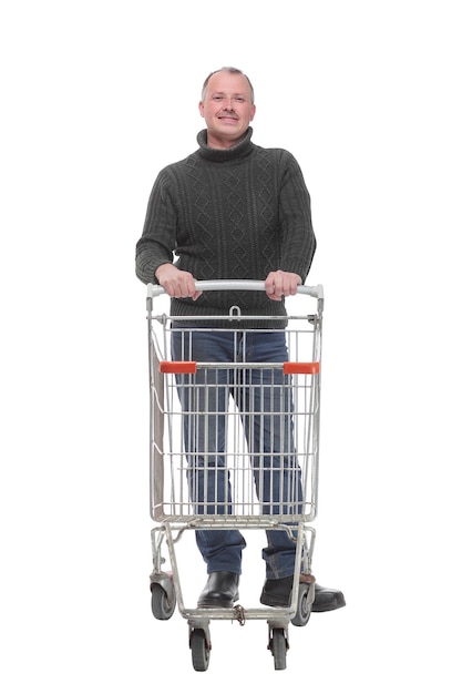 Um retrato de corpo inteiro de um homem empurrando um carrinho de compras vazio isolado no fundo branco