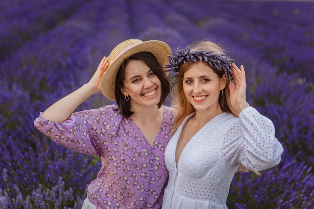 Um retrato de duas mulheres jovens posando em um campo de lavanda com os braços em volta uma da outra