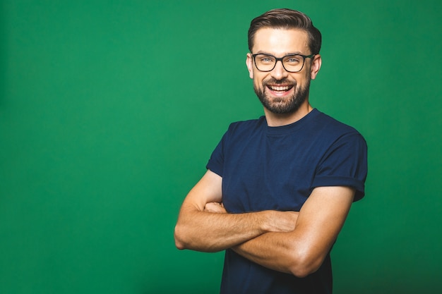 Um retrato de jovem bonito em casual isolado sobre fundo verde com óculos.