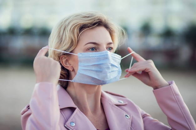 Um retrato de mulher com máscara facial médica ao ar livre. Conceito de pessoas, cuidados de saúde e medicina