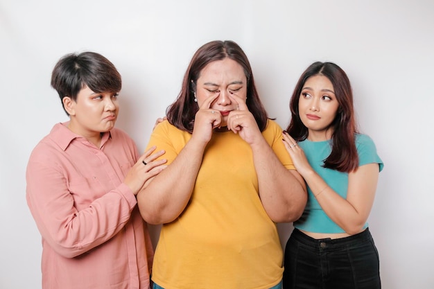 Um retrato de três amigos que parecem tristes chorando enxugou suas lágrimas e se abraçam isolado de fundo branco