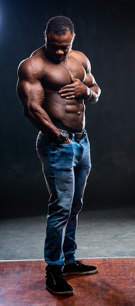 Um retrato de um homem afro-americano forte e bonito, sem camisa contra um fundo escuro foto de estúdio conceito de beleza masculina closeup