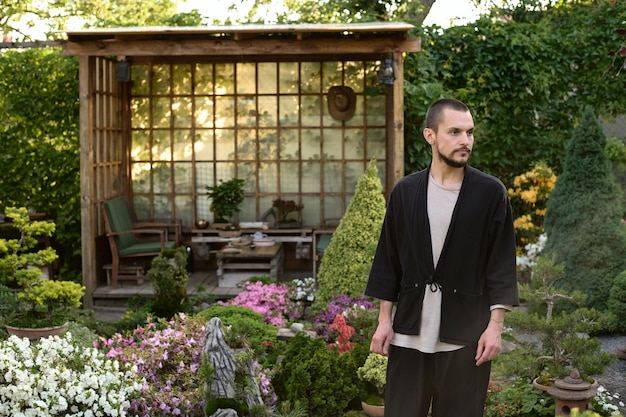 Um retrato de um jovem bonito em um jardim bonsai no fundo de uma casa de chá asiática