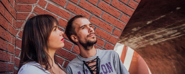 Um retrato de um jovem casal apaixonado posando contra uma parede de tijolos