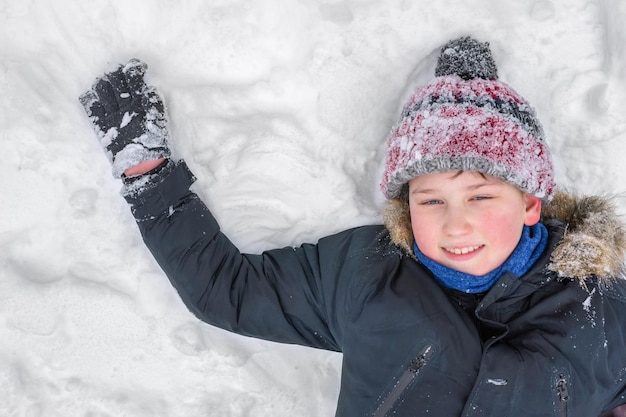 Um retrato de um menino deitado na neve