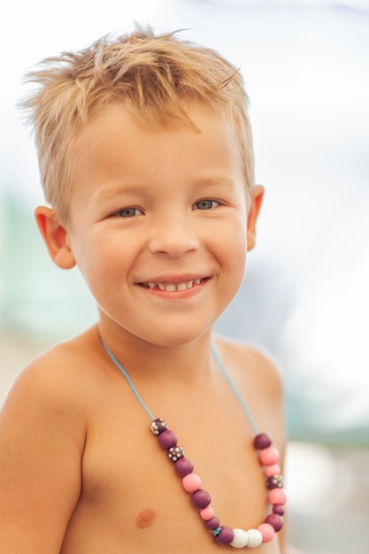 Um retrato de um menino sorridente, vestindo um colar roxo