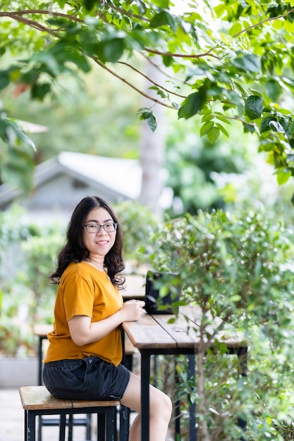 Um retrato de uma bela mulher asiática feliz viajante vestindo estilo de vida hipster elegante vestido laranja amarelo na rua ao ar livre no dia de verão no parque ou sentado no fundo do café