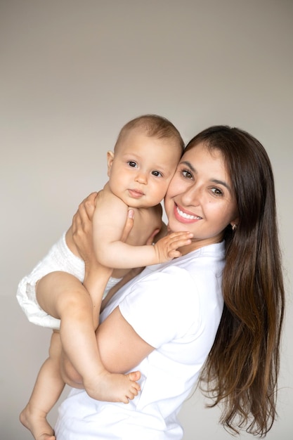 Um retrato de uma linda jovem mãe e seu doce bebê em uma fralda Maternidade Família feliz