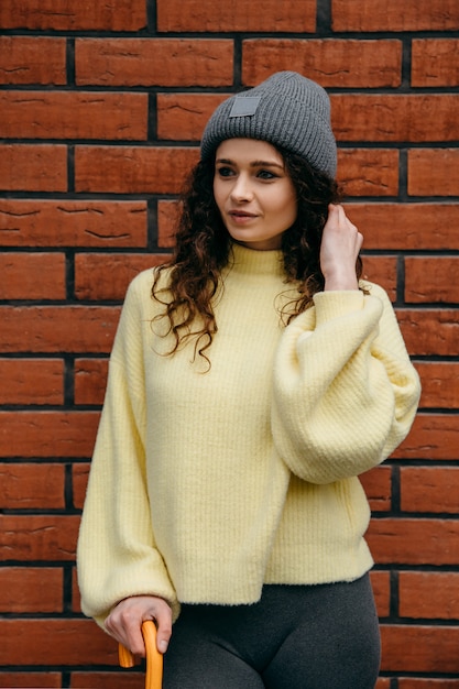 Foto um retrato de uma mulher de cabelos cacheados, vestindo um chapéu e blusa