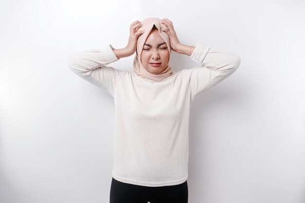 Um retrato de uma mulher muçulmana asiática usando um lenço na cabeça isolado pelo fundo branco parece deprimido