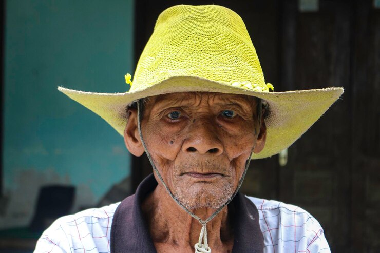Foto um retrato do velho fazendeiro indonésio usa chapéu amarelo com bicicleta velha