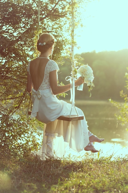 Um retrato suave de uma noiva brilhante rolando em um parque de balanço.