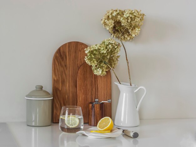 Um ritual matinal para um bom metabolismo é um copo de água com limão na mesa da cozinha com utensílios de cozinha