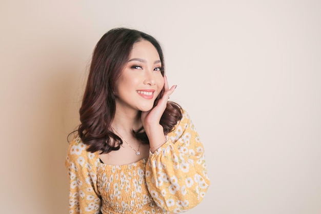 Um rosto alegre de beleza de uma jovem modelo asiática vestindo top floral amarelo Skincare beleza tratamento facial spa conceito de saúde feminina