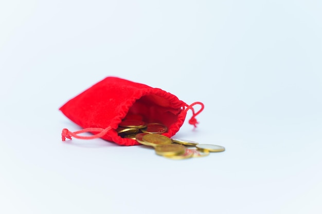 Um saco com moedas de ouro em um fundo branco. O dinheiro está em um saco vermelho.