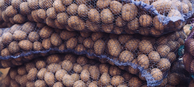 Um saco de batatas cruas e sujas. Close-up de batatas frescas em uma grade.