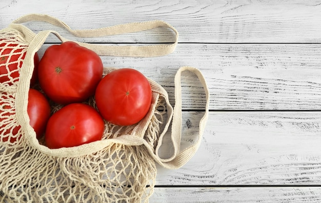 Um saco de malha com tomates em uma mesa de madeira Uma dieta saudável com nutrição limpa