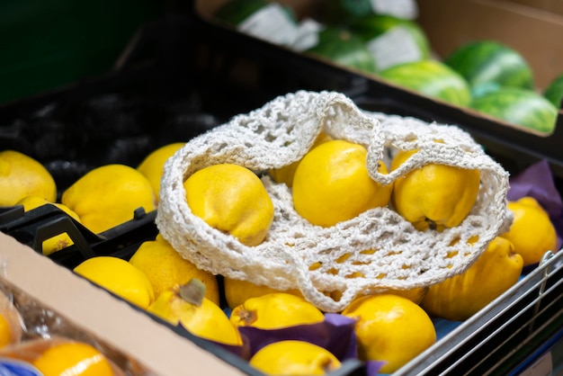 Um saco ecológico de malha com frutas frescas estava em cima da caixa com comida na mercearia local