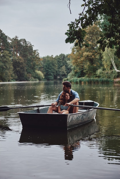 Um sie herumtragen. Schönes junges Paar umarmt sich beim romantischen Date am See