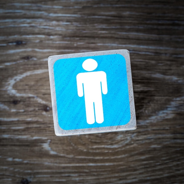 Foto um símbolo ou ícone azul de sinal de banheiro masculino em um bloco de madeira com fundo de madeira e espaço de cópia