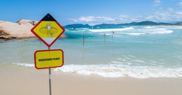 Um sinal de alerta indicando que não é permitido nadar devido às ondas grandes e perigosas do oceano. Copie o espaço.