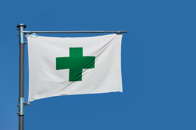 Um sinal transversal verde, bandeira dos primeiros socorros da segurança no fundo do céu azul.